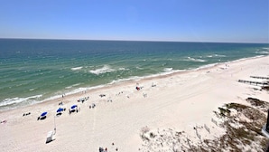 Een strand met heldere lucht, zandstrand en mensen die van het water genieten.