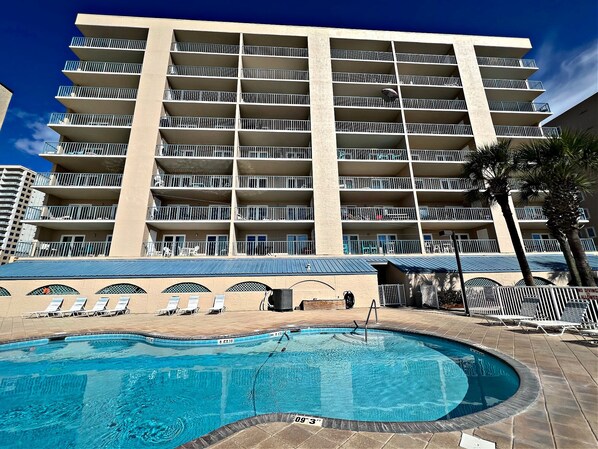 A multi-story hotel with a swimming pool and sun loungers.