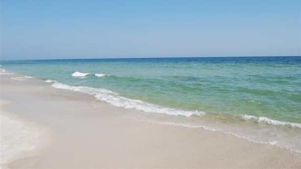 Une plage à l’eau turquoise et limpide, bordée d’un rivage sablonneux.