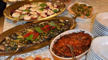 Una mesa de bufé con diversos platos, incluyendo pasta, ensaladas y productos de pastelería.