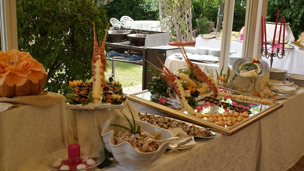 A buffet table with various food items and a decorative centerpiece. - La Villa dei Gourmets (Foggia)