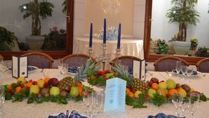 A dining table set with a fruit centerpiece, candles, and a menu. - La Villa dei Gourmets (Foggia)