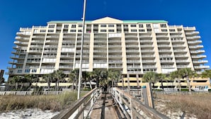 Ein mehrstöckiges Hotel mit Balkonen, einer Holzpromenade, die zum Eingang führt, und Palmen im Vordergrund.