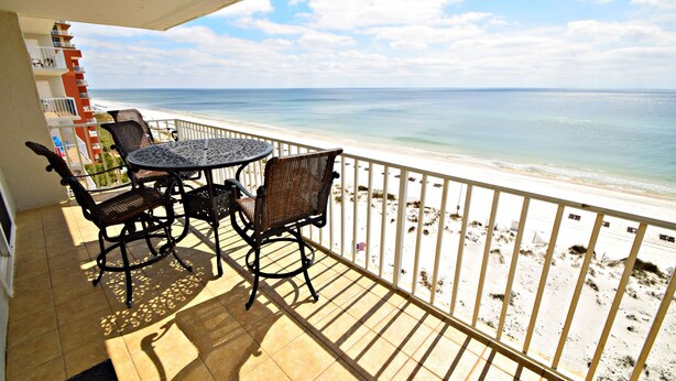 A balcony with a table and chairs overlooking a beach. - 🌞Make waves with a Beach Getaway!  Come enjoy the breeze! (Gulf Shores)