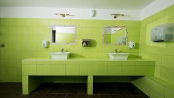 A bathroom with green tiles, two sinks, and two mirrors.