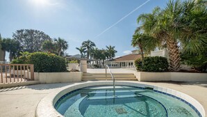Una piscina circular con una escalera metálica, rodeada por un muro bajo y palmeras.