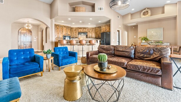 A spacious living room with a brown leather sofa, blue armchairs, and a coffee table.
