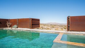 A clear pool with wooden fences and a desert landscape in the background.