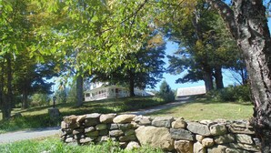 A stone wall, a white house with a porch, and a large tree. - 70 Private Acres-SKI! SKI! SKI! (Athol)