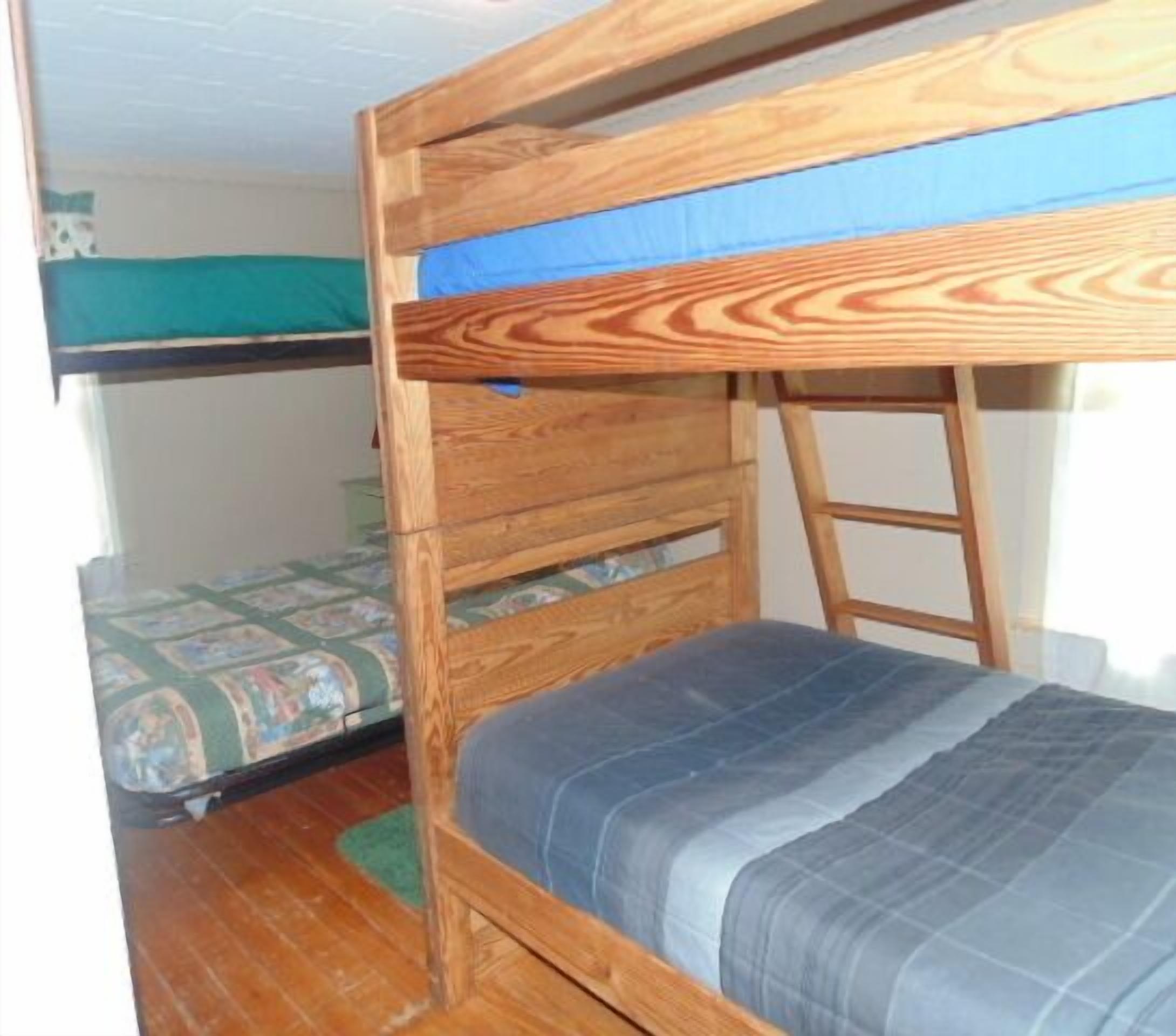A bunk bed with a wooden frame and a blue mattress.