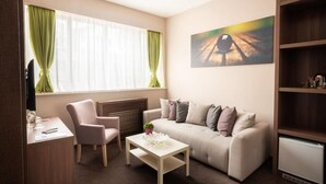 A modern living room with a sofa, a coffee table, a chair, and a TV. - Veneti Suites (Belgrade)