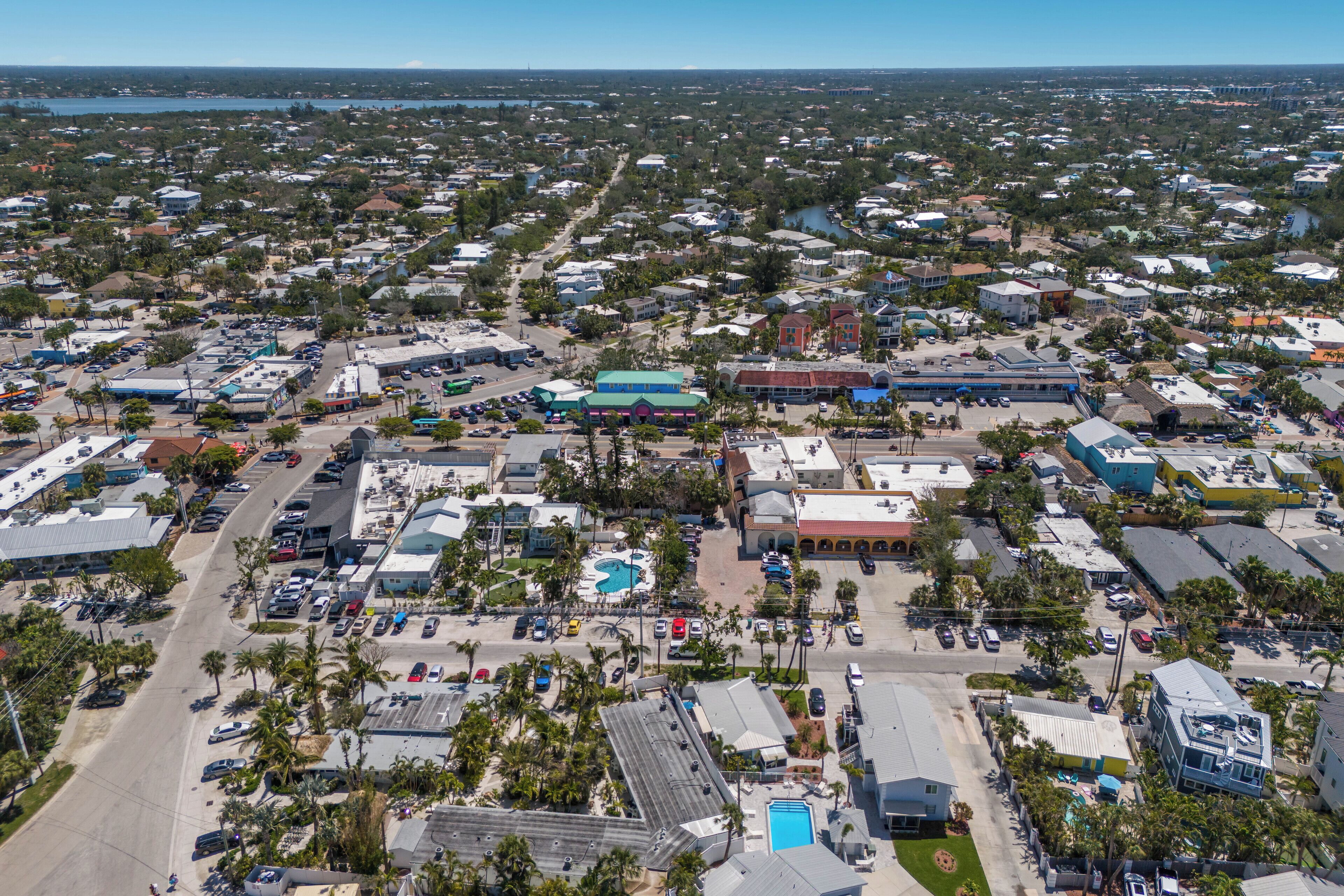 An aerial view of a coastal town with a central plaza, various buildings, and a large body of water in the background.