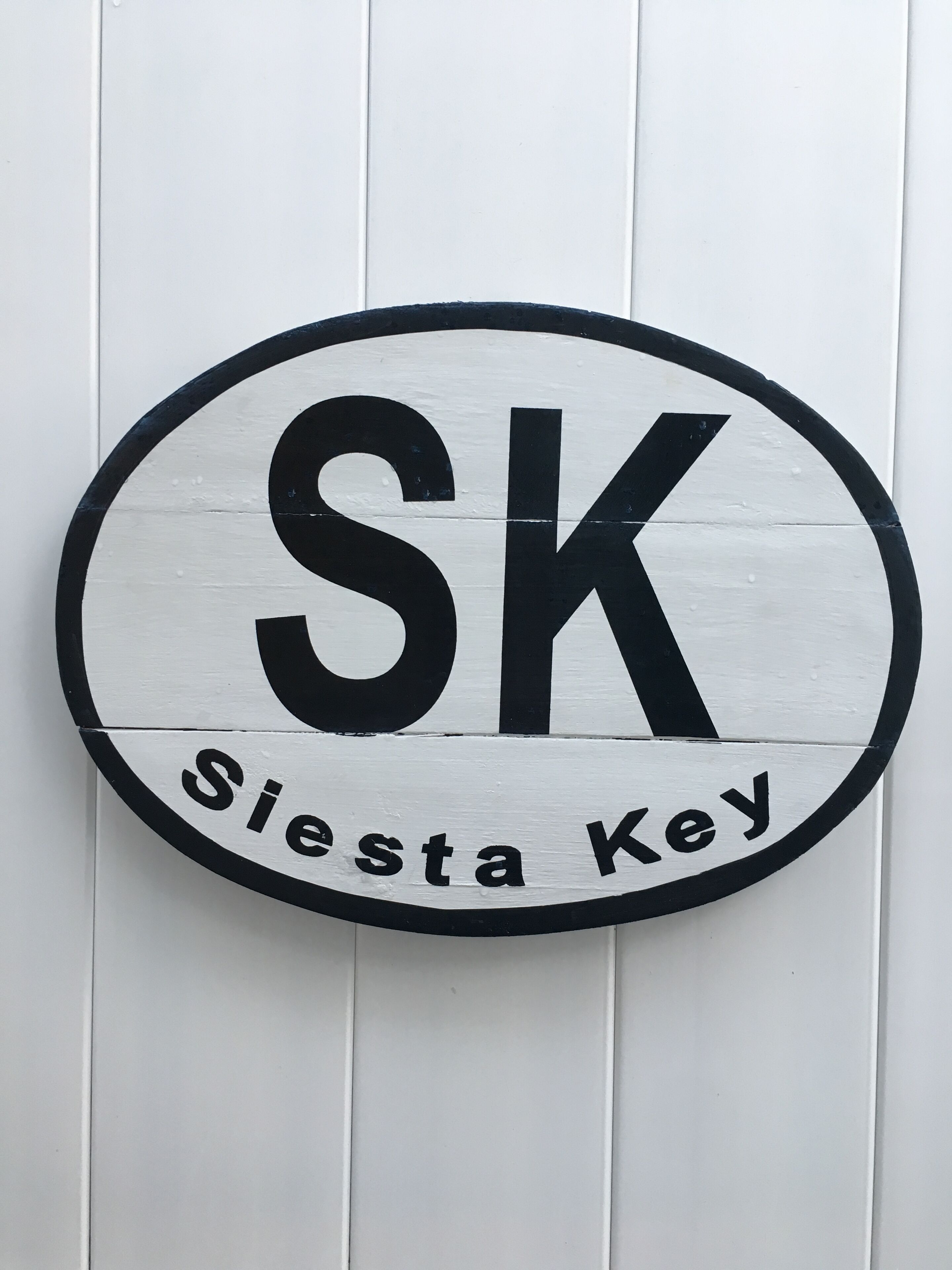 Een rond bord met de letters 'SK' en de tekst 'Siesta Key'.