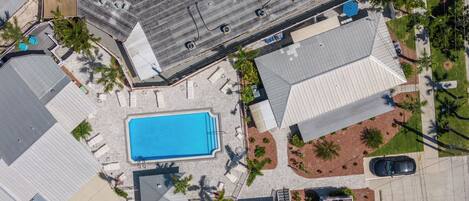 Vista aérea de una zona residencial con piscina, varios coches y algunas palmeras.