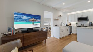 A modern kitchen with white cabinets, a built-in microwave, and a large island with a sink. - Perfect Local In Village,1 1/2 Block From #1 Beach In USA, Pool, Wifi, Sun & Fun (Siesta Key)