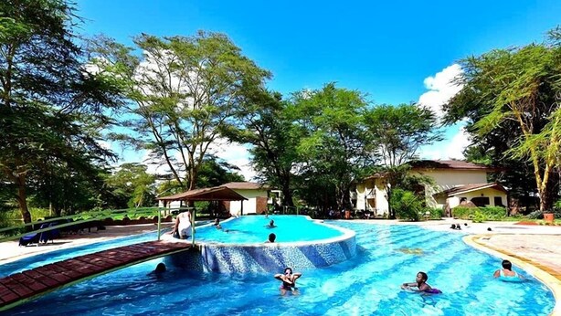 A large outdoor swimming pool surrounded by trees and a few buildings. - Hunters Lodge - Kiboko (Kiboko)