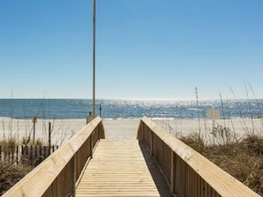 Un muelle de madera que conduce a una playa bajo un cielo despejado.