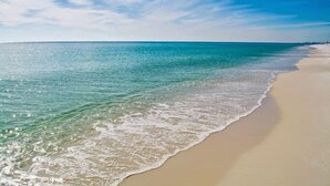 Ein Strand mit klarem türkisblauem Wasser und einem breiten Sandstrand.