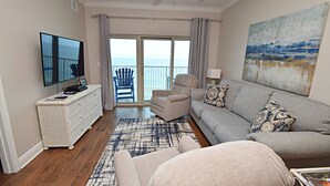 Ein Wohnzimmer mit einer Couch, einem Sessel und einem Flachbildfernseher.