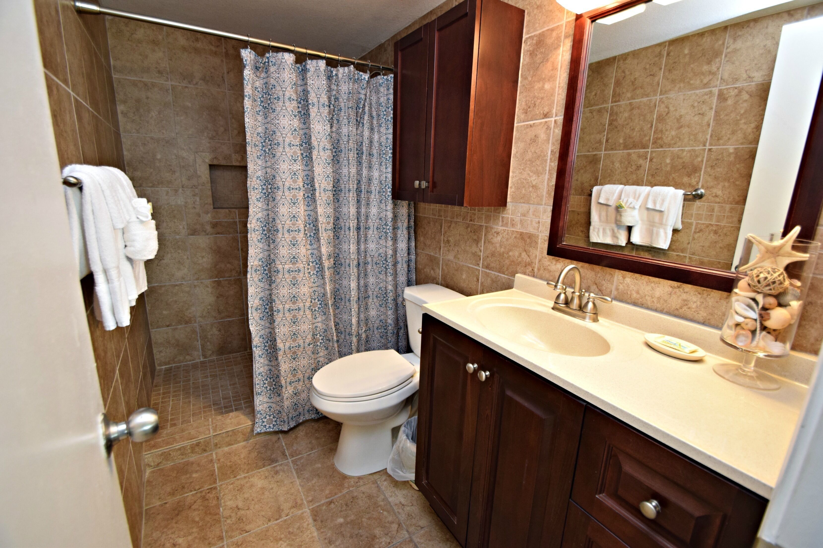 A bathroom with a toilet, shower, and sink.