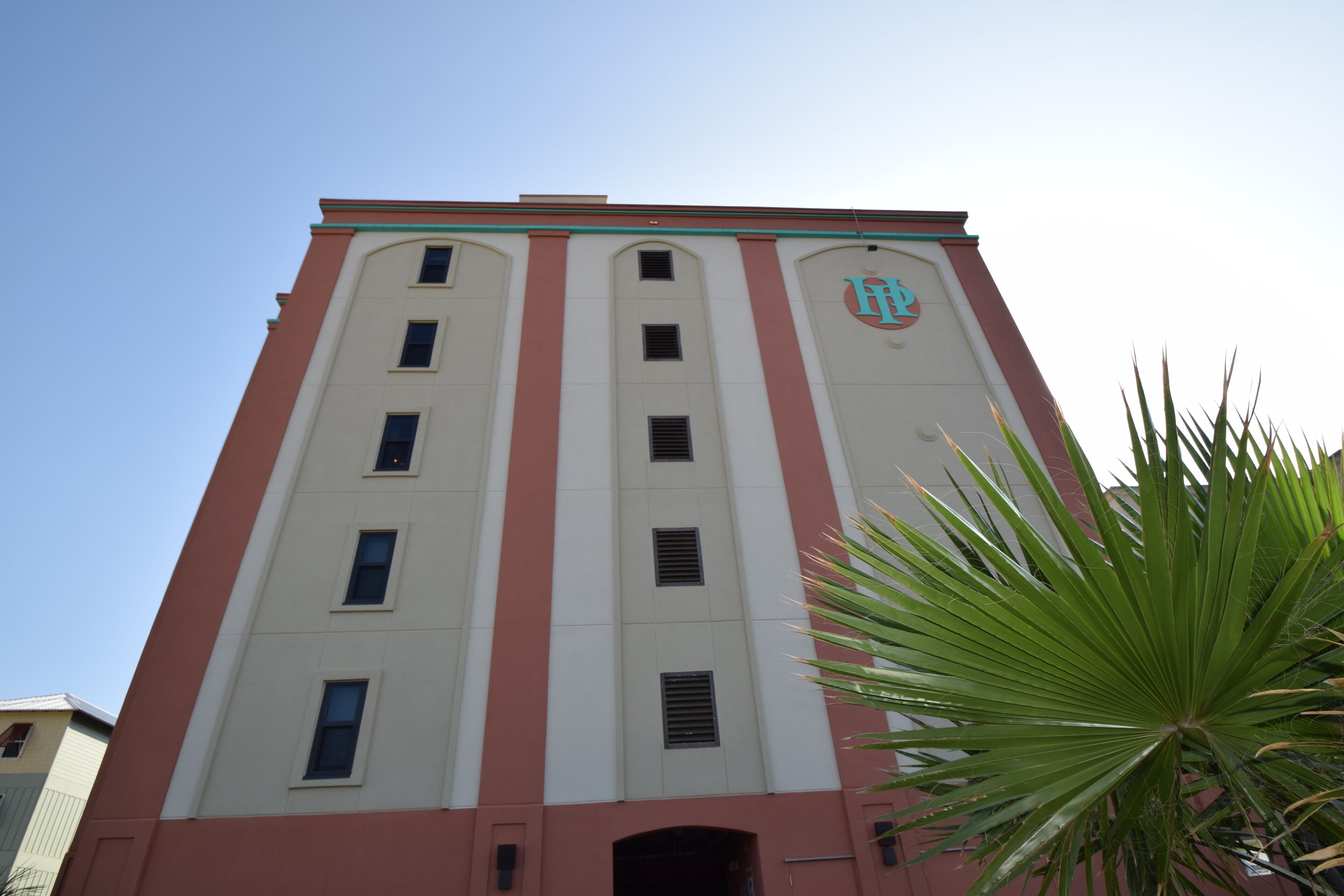 Un edificio alto con fachada roja y blanca, que presenta un logotipo en el lateral.