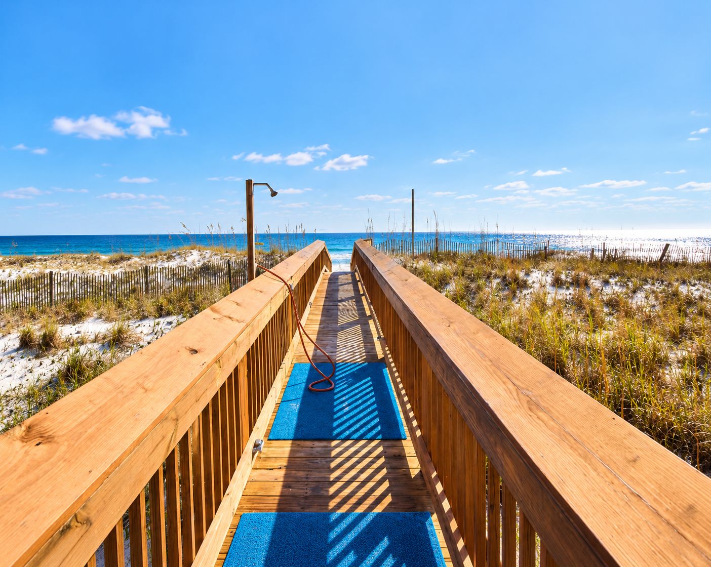 A wooden boardwalk leading to a beach with a clear sky.
