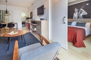 Moderni hotellihuone, jossa on sänky, työpöytä ja ruokailutila.