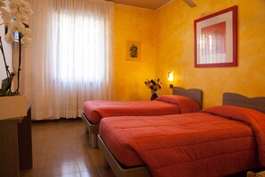 Two single beds with matching bedding, a bedside table, and a wall-mounted picture frame adorn this stylish room.