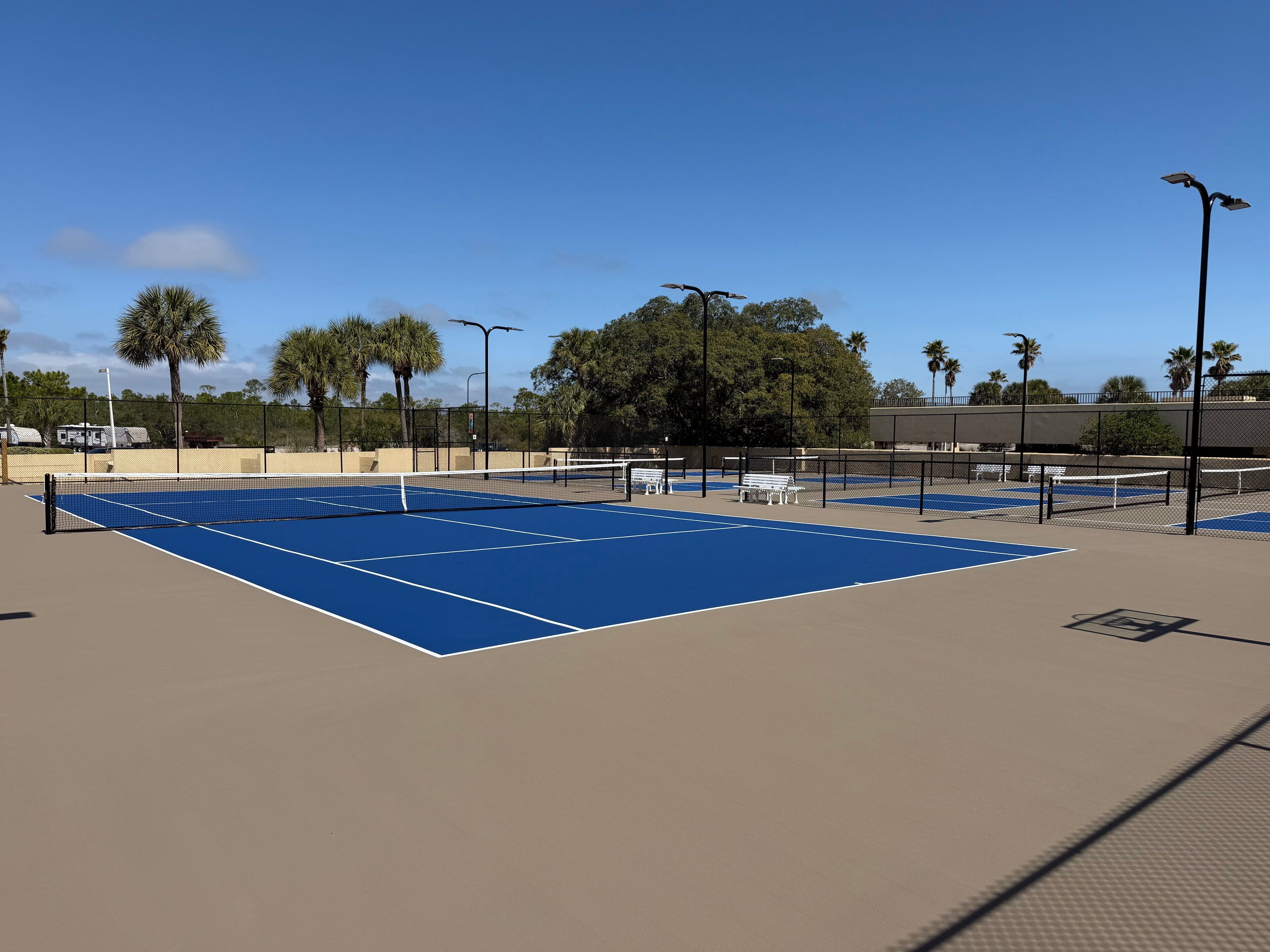 Ein Tennisplatz mit Netz, Bänken und Zaun.