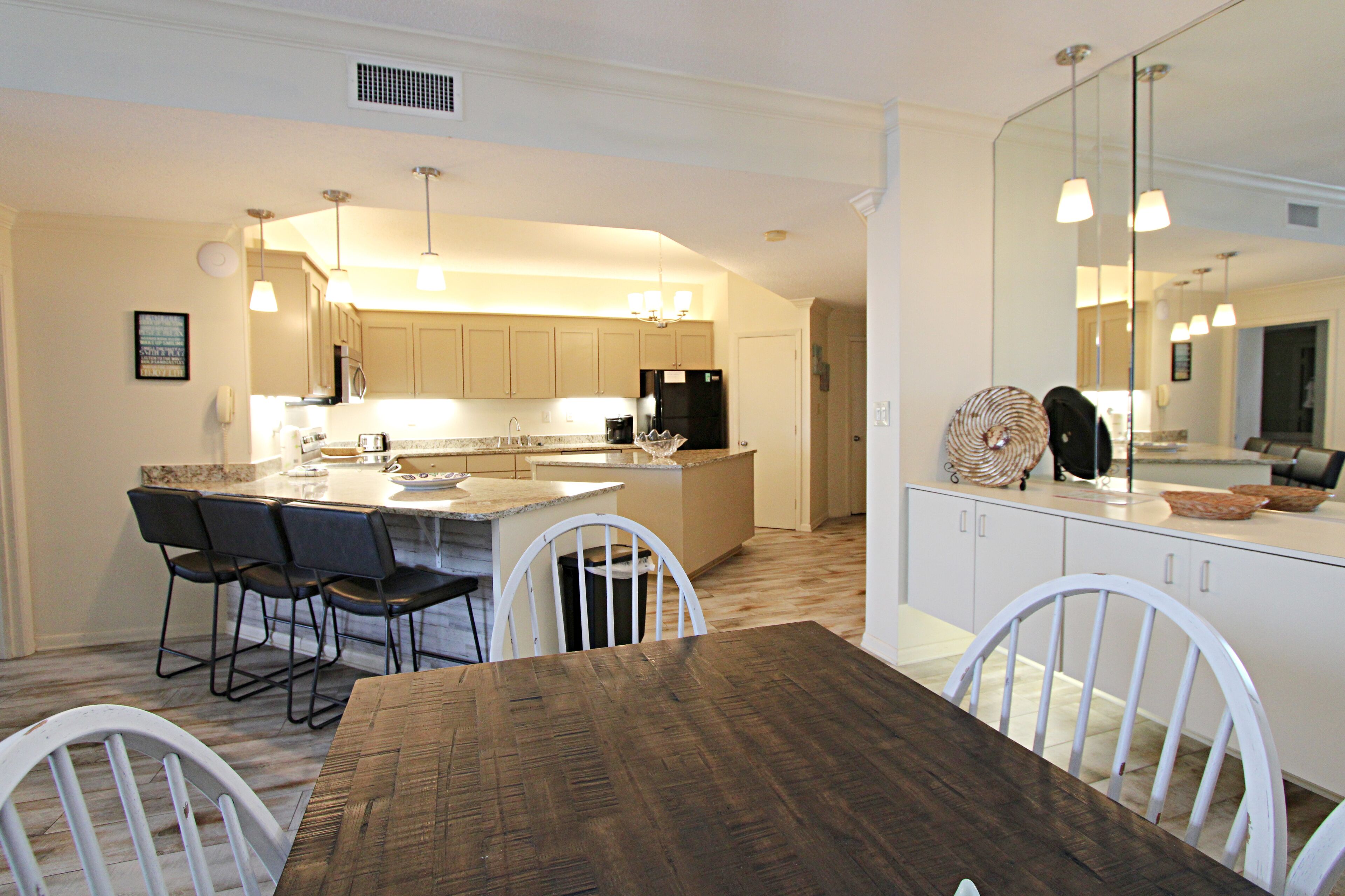 A modern kitchen with white cabinets, a central island, and bar stools.