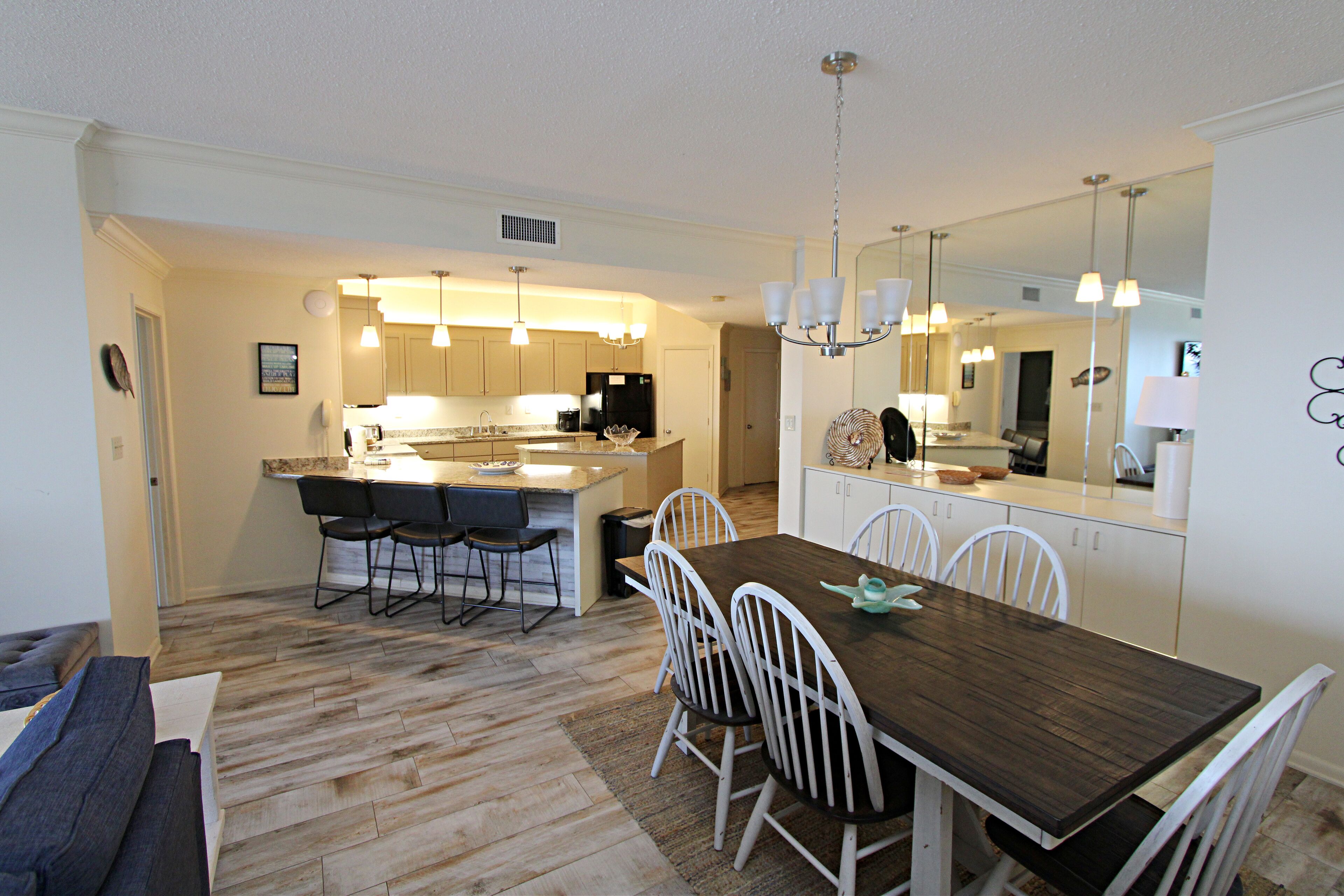 A modern kitchen with a central island, white cabinetry, and pendant lighting.