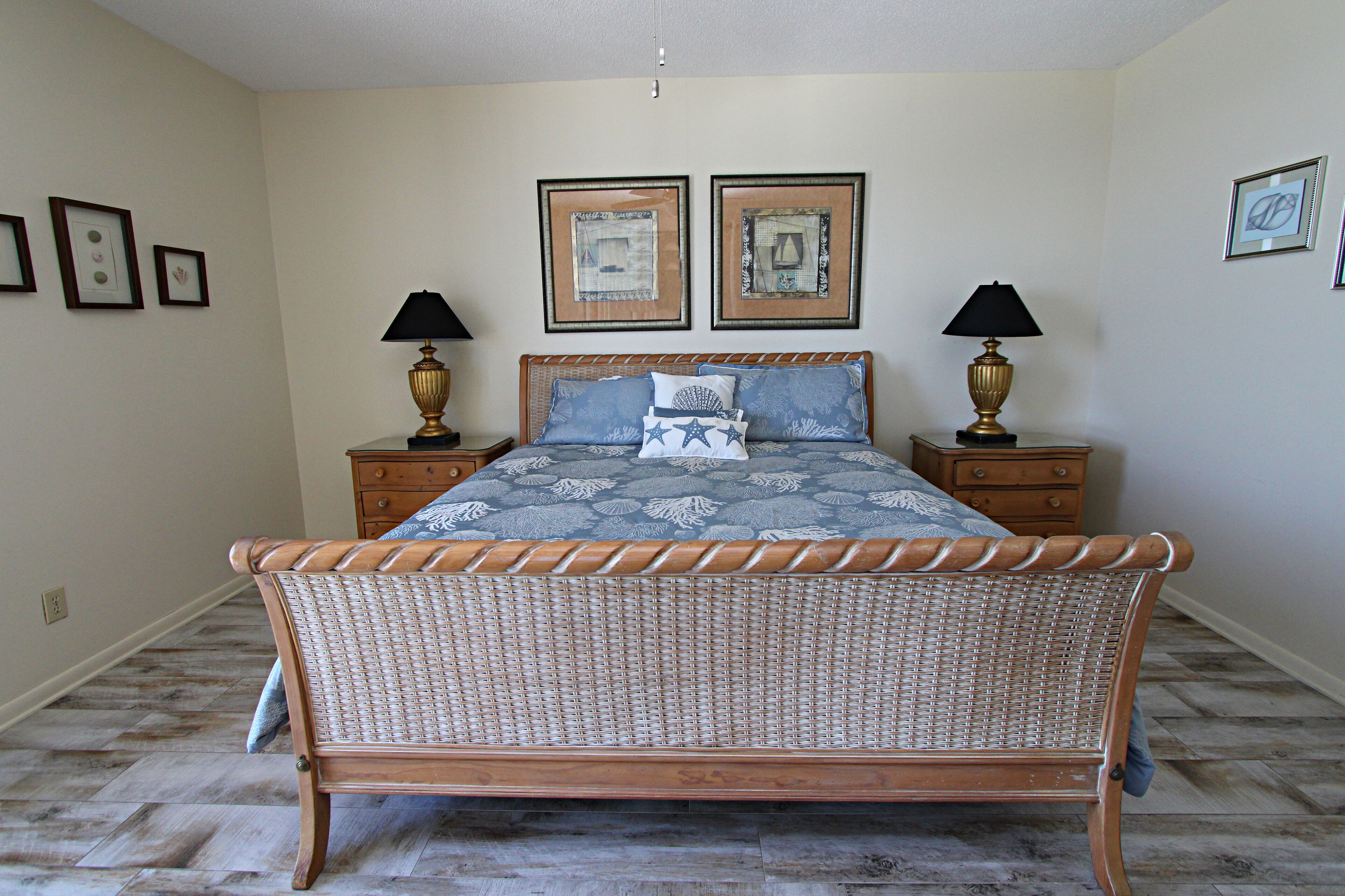 A bedroom with a wooden bed, two bedside tables with lamps, and framed pictures on the wall.