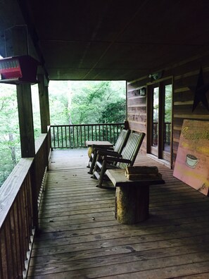 Eine Holzterrasse mit Bänken und einem Mülleimer, mit Blick auf eine bewaldete Gegend.