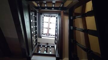 A narrow stairway with metal railings leading to a bright room with a large window.