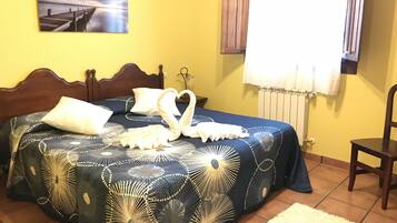 A bedroom with a bed, a wooden headboard, a wall-mounted picture, a window with curtains, and a chair.