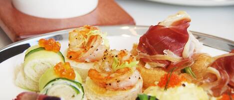 A variety of appetizers on plates, including seafood, caviar, and other small dishes.