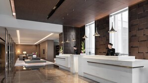 Una zona d'entrada moderna amb sòl de marbre, un taulell de recepció i il·luminació penjant.