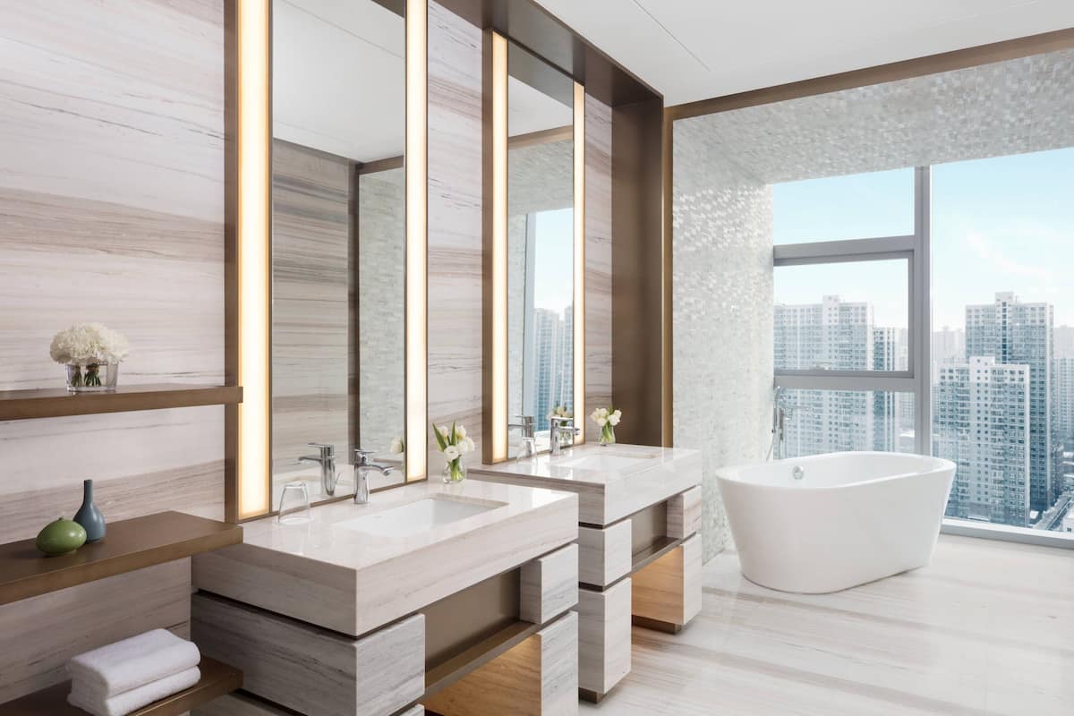 A modern bathroom with two sinks, a freestanding bathtub, and large mirrors.