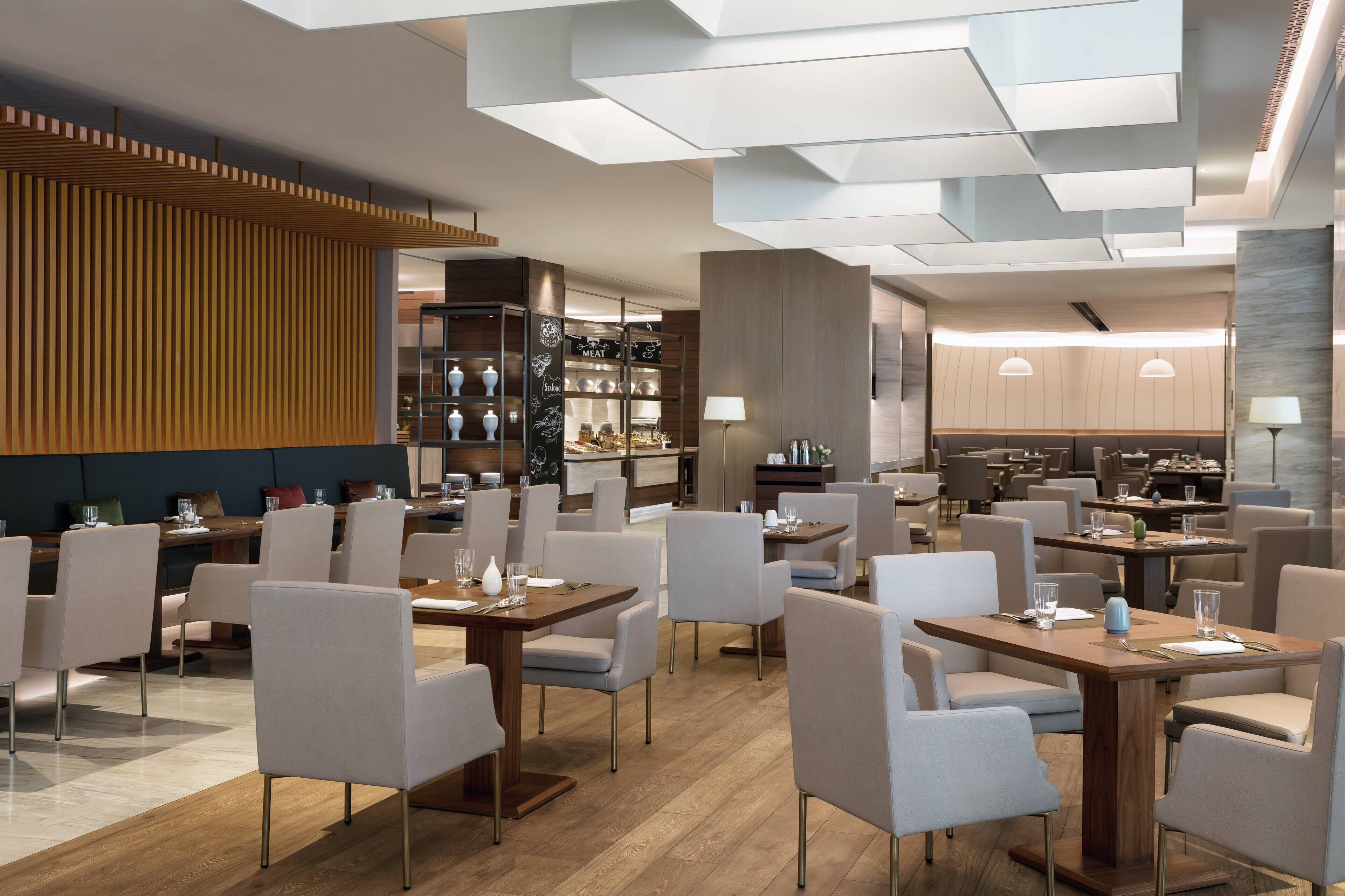 Un restaurant moderne offrant différents types de sièges, notamment des tables et des chaises, et doté d’un bar bien visible.