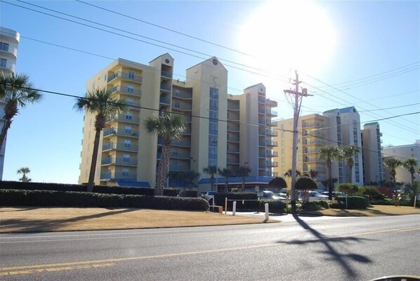 A multi-story hotel with balconies, palm trees, and a clear sky. - 👣 Come get your toes in the sand ~~~ and a cold drink in your hand! 🍹 (Gulf Shores)