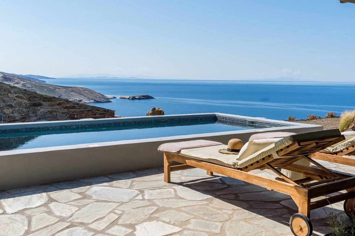 A stone-tiled patio with a pool overlooking the sea.