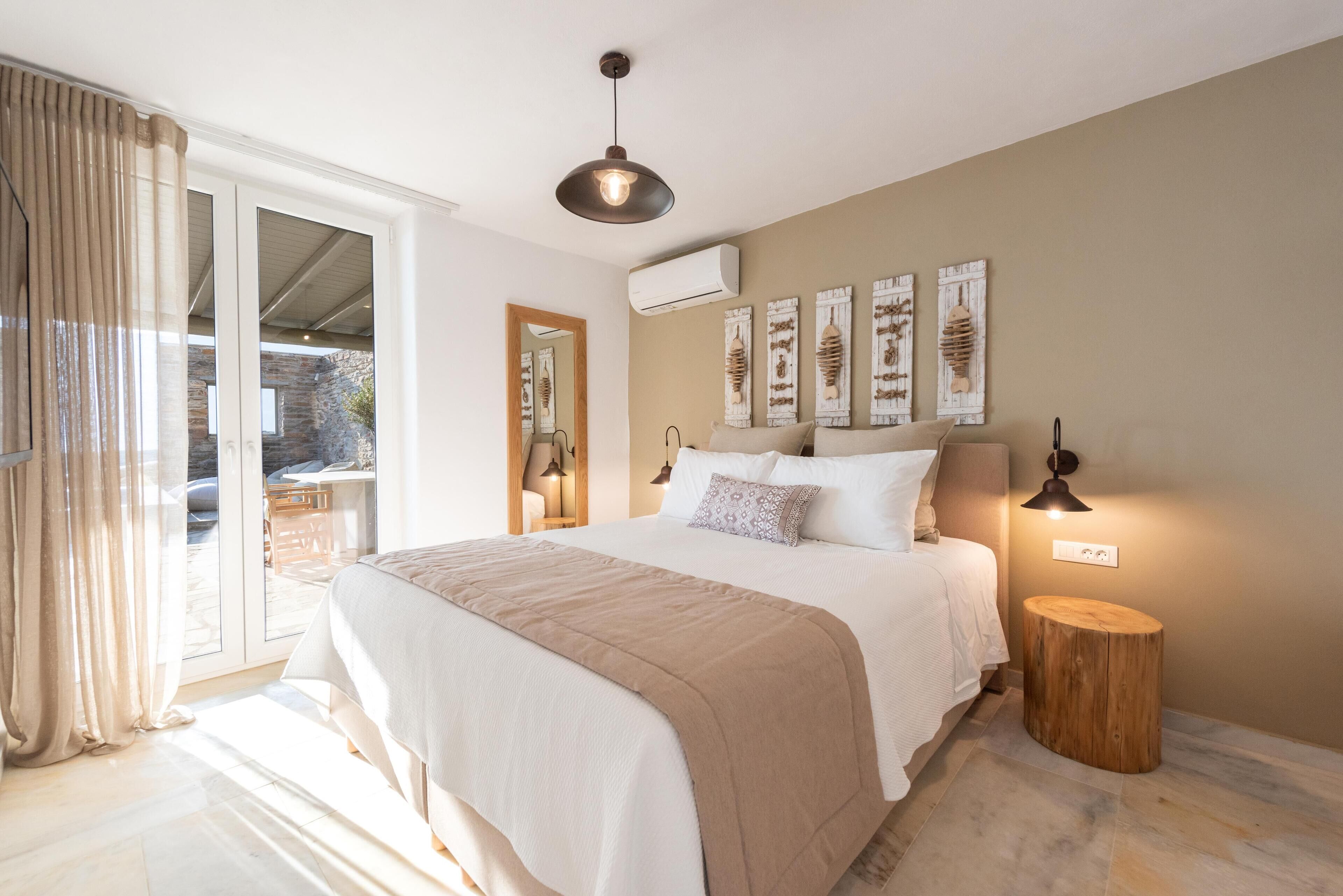 Un dormitorio con una cama grande, una mesita de madera redonda, una lámpara del techo y decoración en la pared.