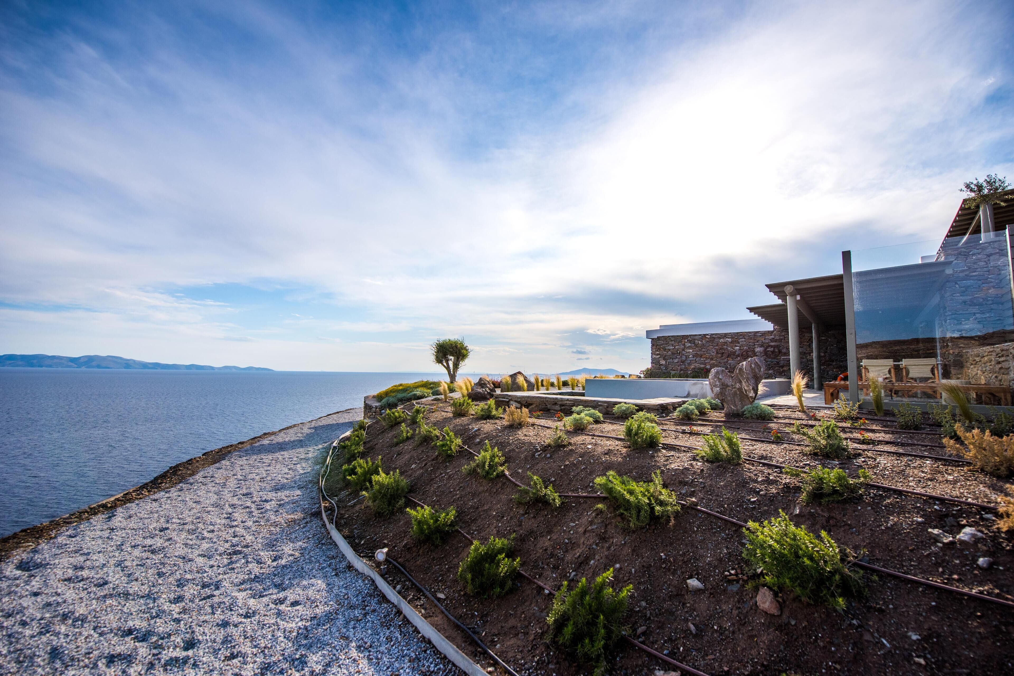 A coastal property with a garden terrace overlooking the sea, a stone building, and a clear sky.