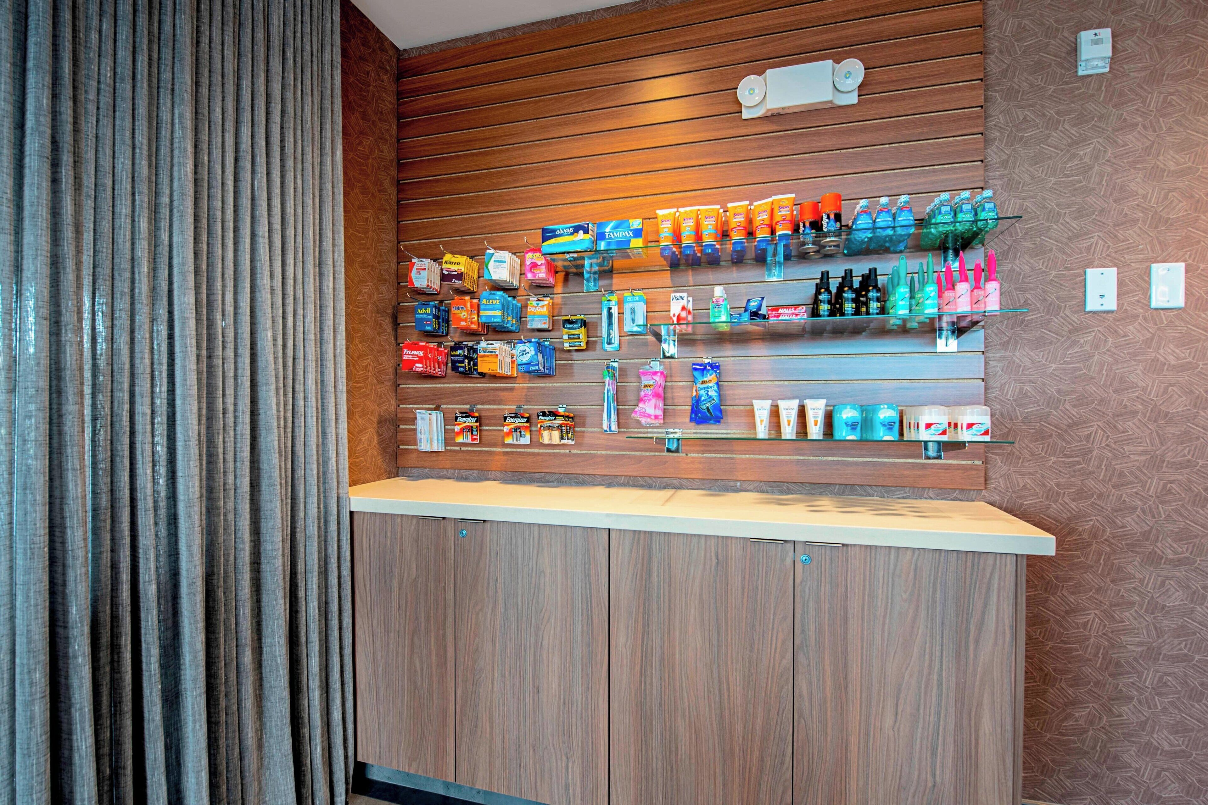 A hotel reception area with a wooden counter, shelves stocked with toiletries, and a patterned wall.
