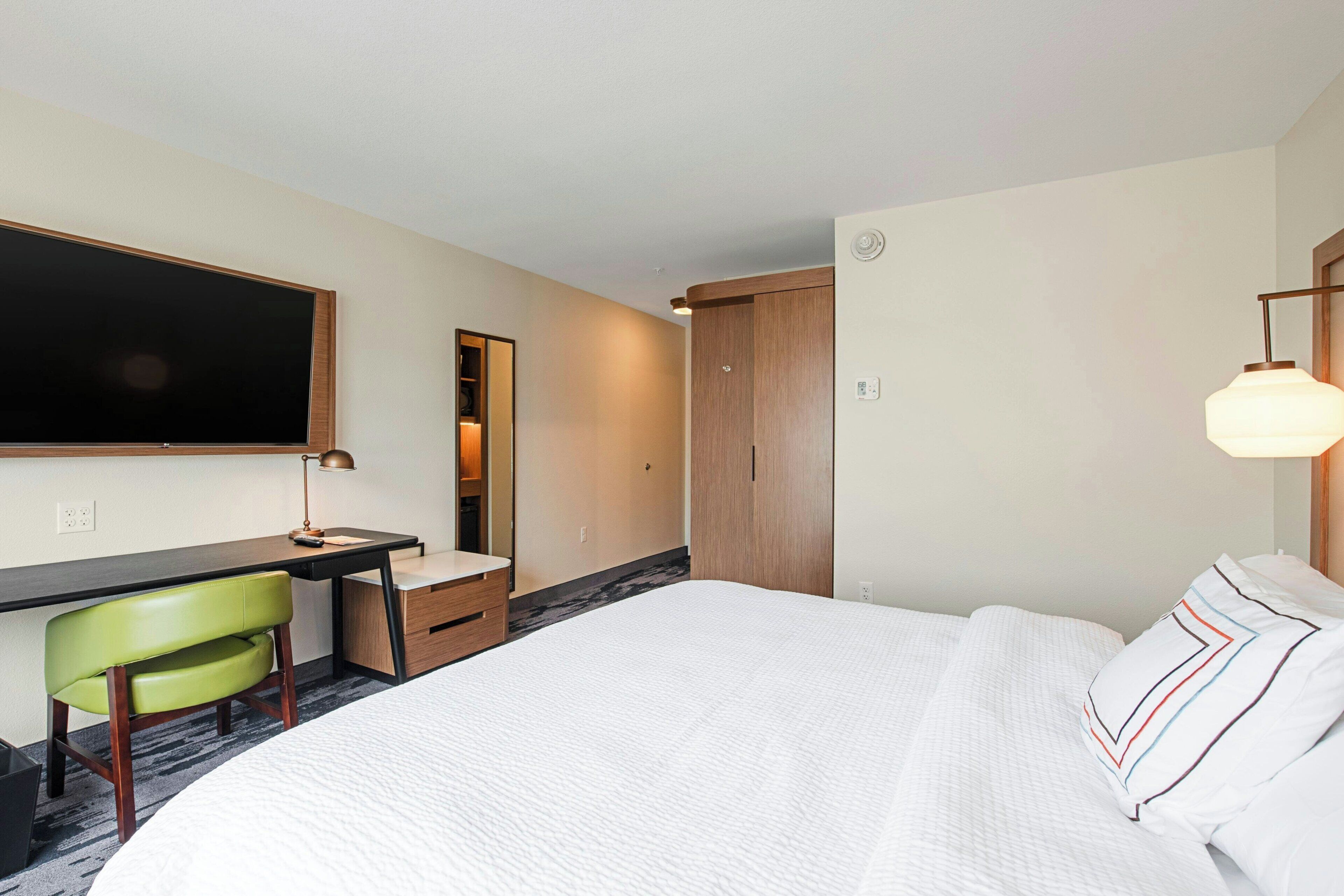 Una habitación de hotel con cama, escritorio, silla y armario.