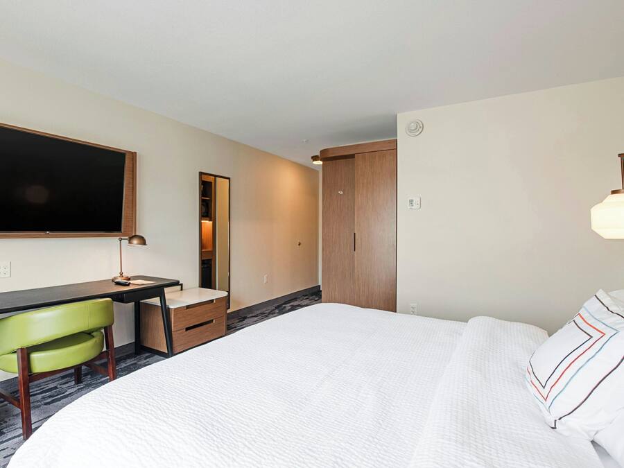 Una habitación de hotel con cama, escritorio, silla y armario.