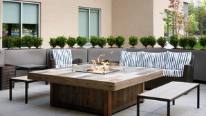 An outdoor seating area with a fire feature, a sofa, and a table.