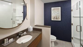 Een moderne badkamer met een grote spiegel, een wastafel, toilet en een douchehoek.