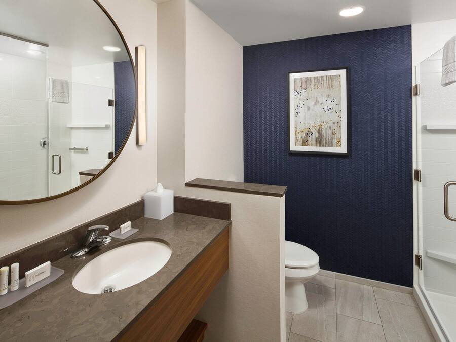 A modern bathroom with a large mirror, a sink, a toilet, and a shower area.