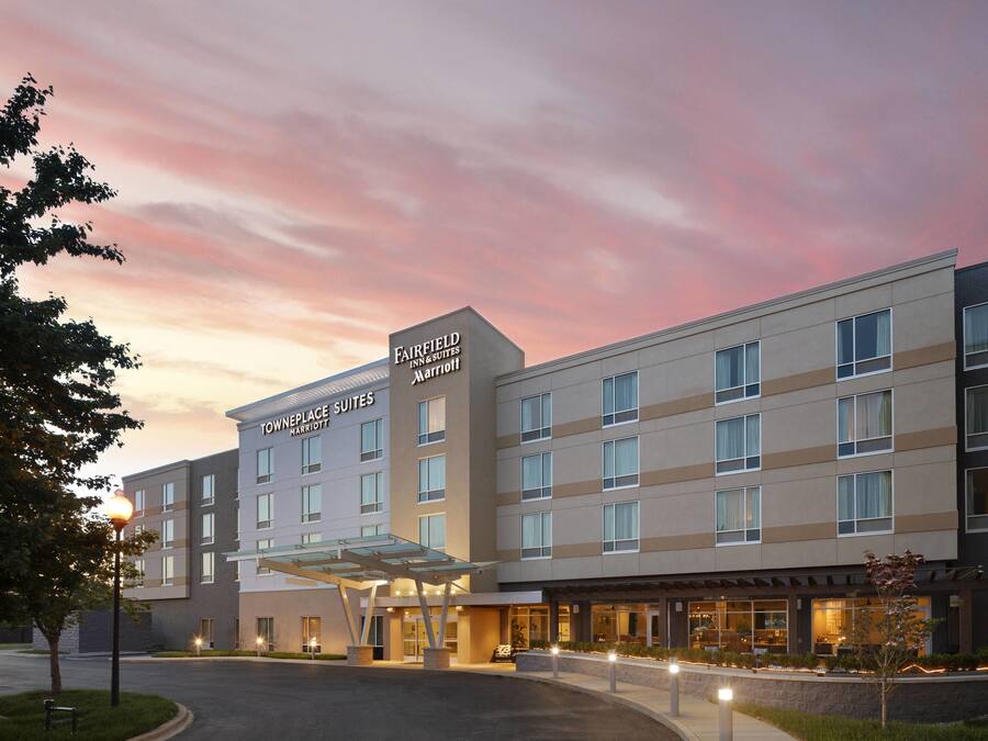 Fairfield Inn & Suites by Marriott -hotelli, jossa on moderni muotoilu, katettu sisäänkäynti ja kauniisti maisemoitu etupiha.